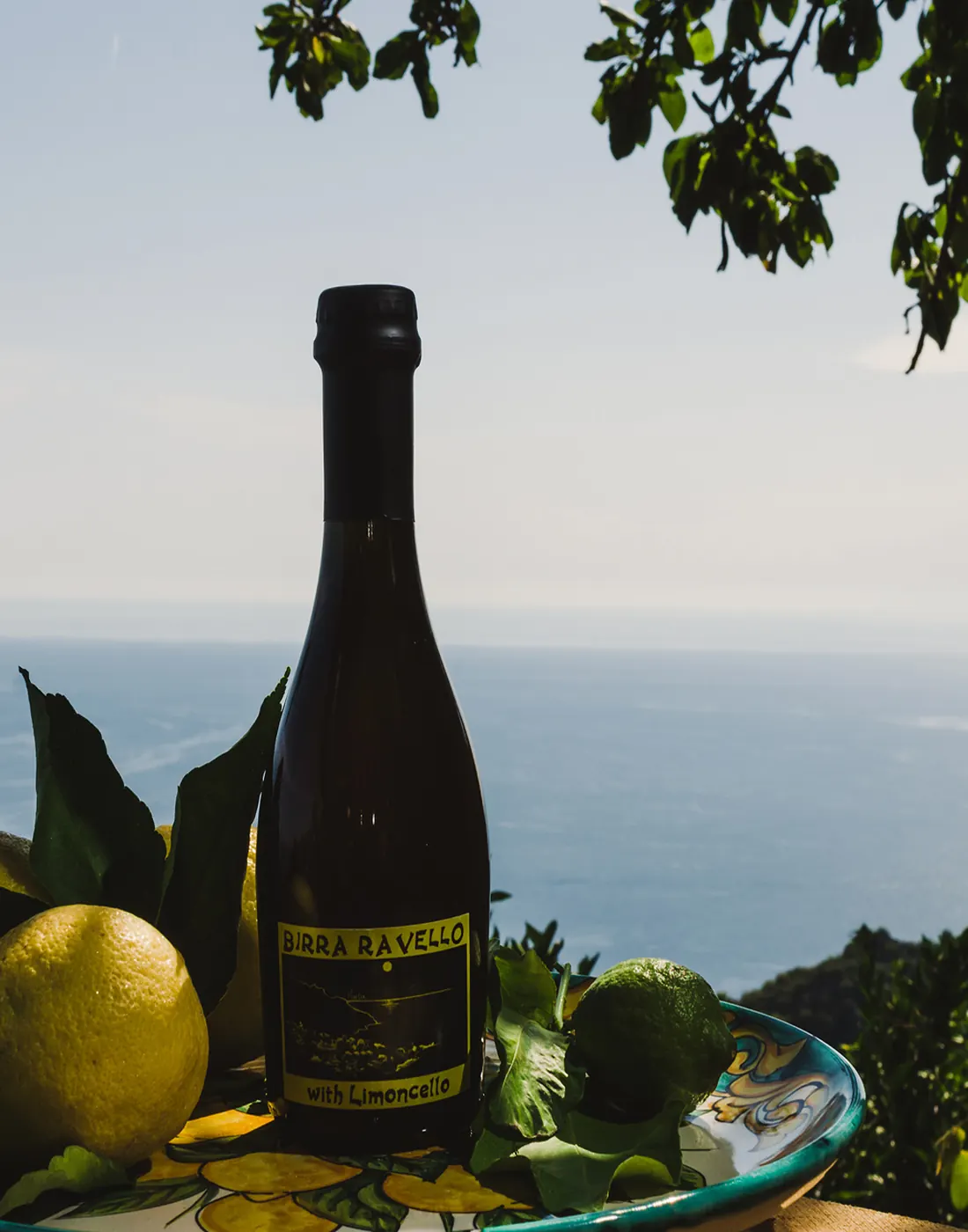 Una bottiglia di Birra Ravello con i limoni, davanti al mare